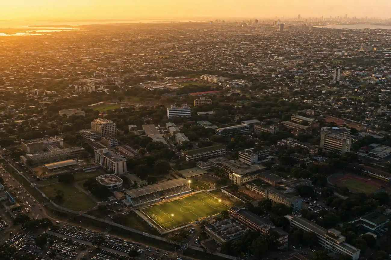 Aerial view of West African city and university campus with football pitch at golden hour